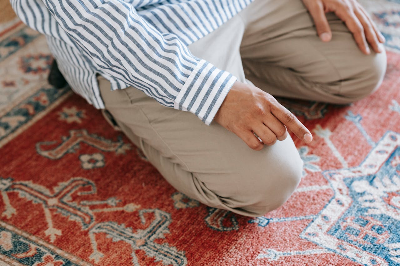 Services Close-up of a man kneeling on a patterned rug, highlighting Islamic prayer traditions.